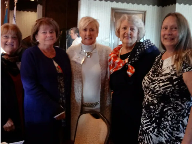 Five women posing together at a committee event